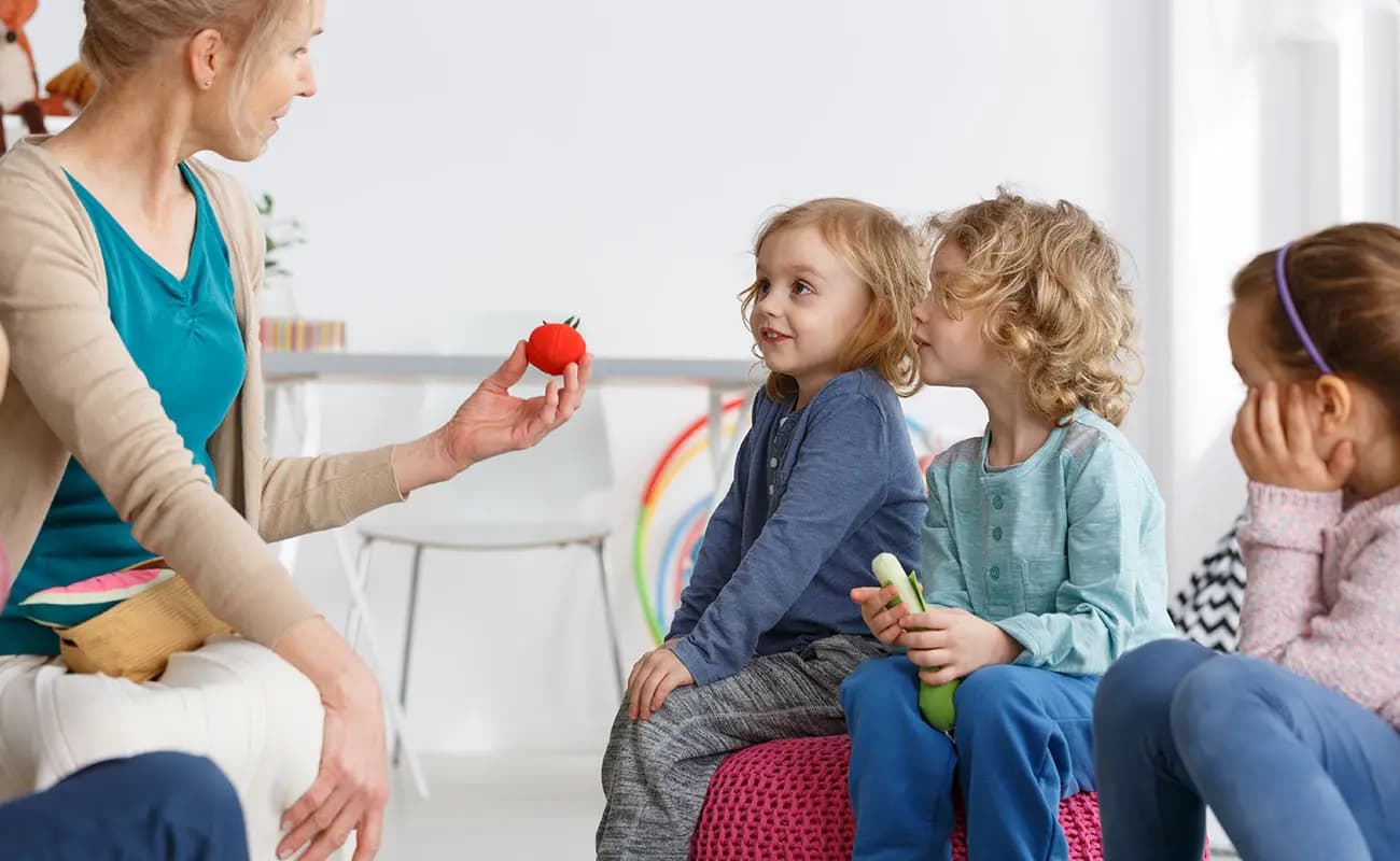 Teacher sharing colourful learning toys with young children
